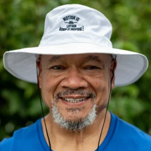 Smiling man in white hat, outdoors.