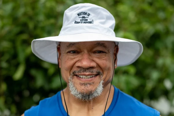 Smiling man in white hat, outdoors.