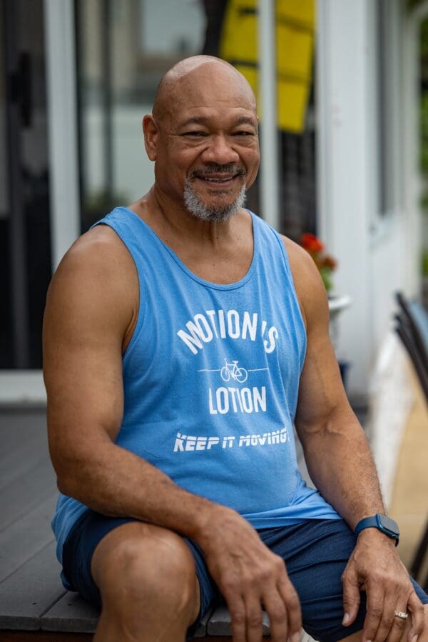 Smiling man in Motion's Lotion tank top.