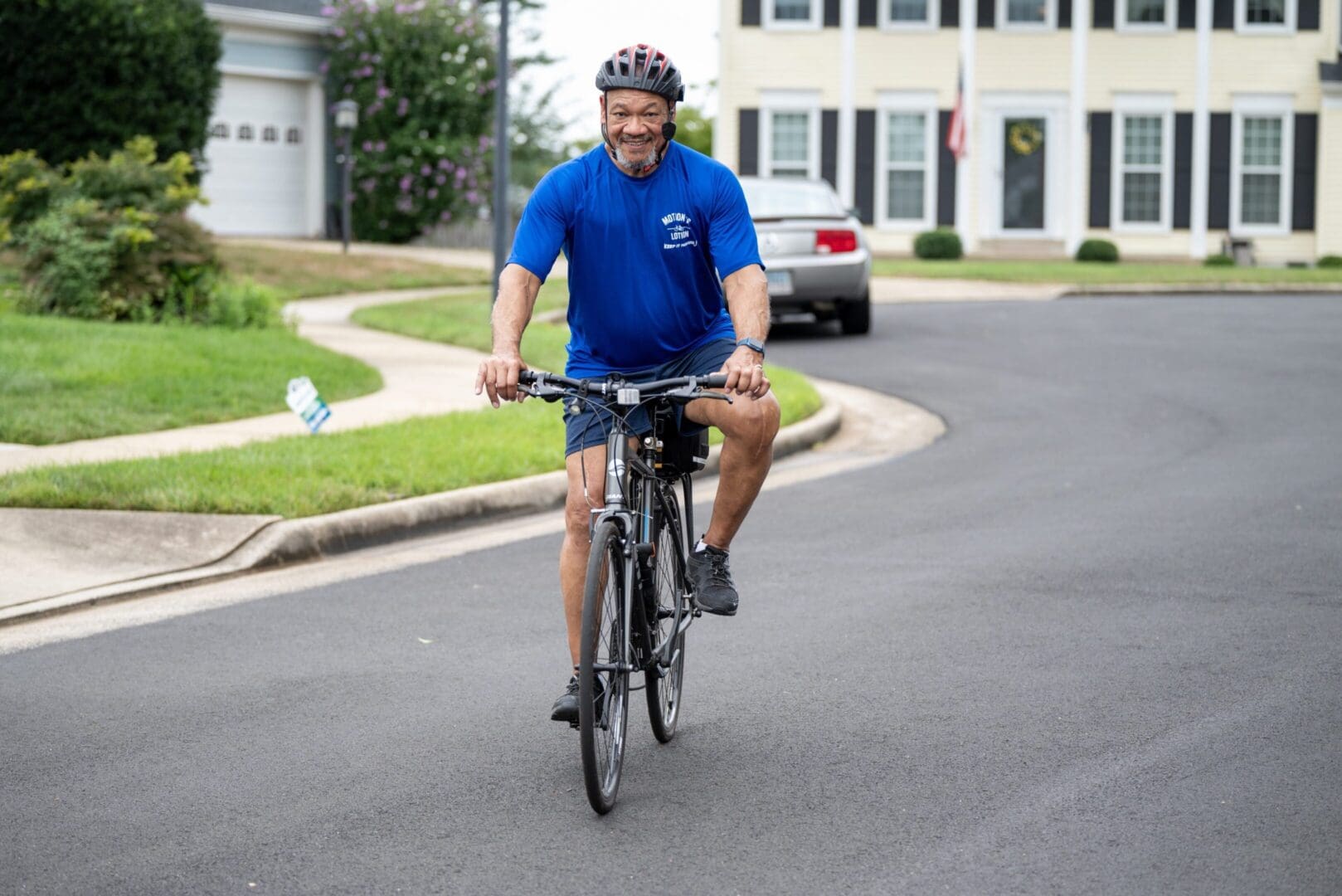 Smiling man cycling down residential street.