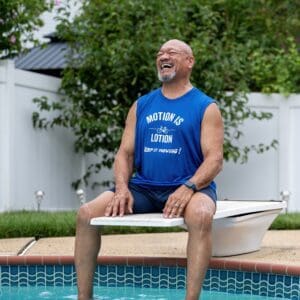 Here's an alt tag for the image: Happy man sitting by pool.