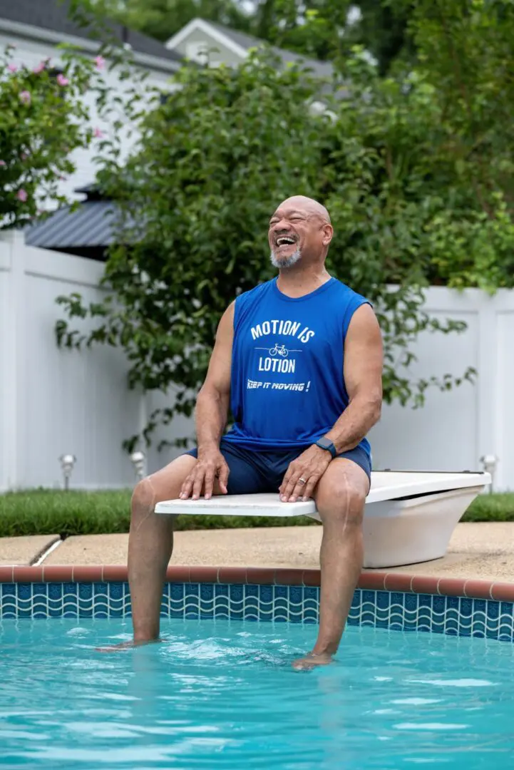 Here's an alt tag for the image: Happy man sitting by pool.